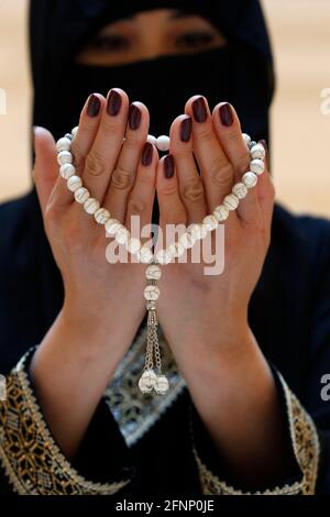 Close up view of a Muslim woman hands in abaya while holding rosary with her hands and praying. Religion praying concept. United Arab Emirates Stock Photo