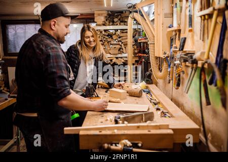 carpenter communicates with woman customer in his workshop Stock Photo