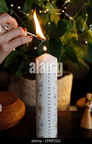 Woman lighting a christmas advent candle.  France. Stock Photo