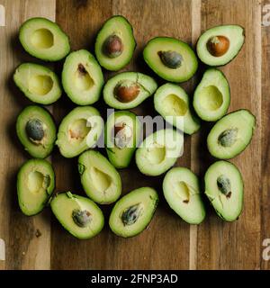 Sqaure crop of cut avocados on a wooden cutting board Stock Photo