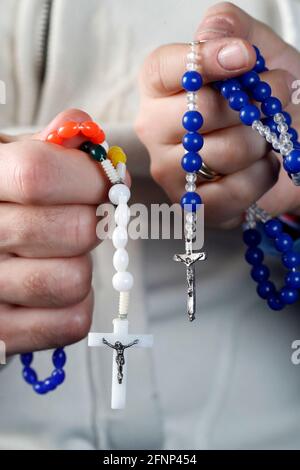 Catholic man and woman praying together at home. Close up on hands with prayer beads.   France. Stock Photo
