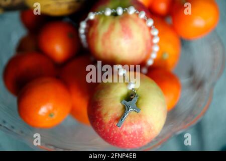 Prayer beads with crucifix on apples. Religious symbols.  France. Stock Photo