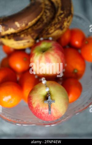 Prayer beads with crucifix on apples. Religious symbols.  France. Stock Photo