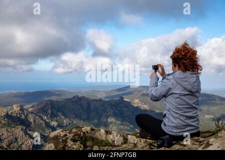 Woman using a camera on top of Arcuentu mountain, Sardinia, Italy Stock Photo