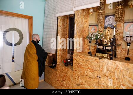 Zen dojo in Marrubiu, Sardinia, Italy. Master lifting the altar curtains Stock Photo