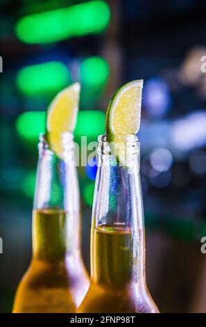 Cold light beer in bottles on the bar. Lime wedges cover the necks of the bottles. Mexican beer. Stock Photo