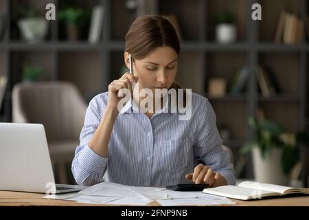 Pensive millennial woman accountant focused on paperwork prepare financial report Stock Photo