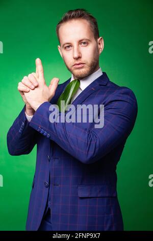 Self assured male in elegant suit and green leaf tie pointing at camera while looking at camera and showing concept of eco friendly business Stock Photo