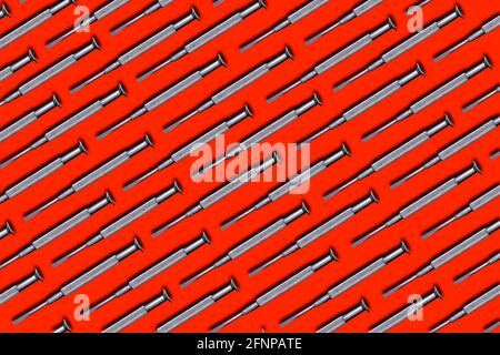 Mini screwdriver of steel. Creative pattern. Isolate on red background. Instrument for work. Top view. Stock Photo