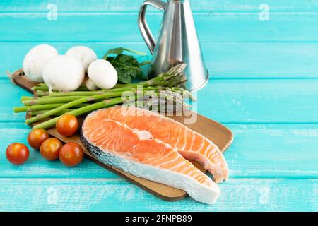 Raw salmon slice with vegetable decoration on blue background. Copy space. Stock Photo