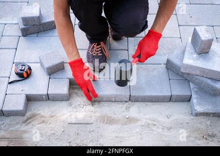 The master in yellow gloves lays paving stones Stock Photo