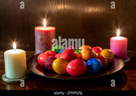 Painted Easter eggs and candles, multicolored, vintage, on a wood table Stock Photo