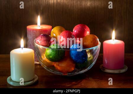 Painted Easter eggs and candles, multicolored, vintage, on a wood table Stock Photo