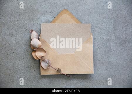 Blank kraft brown invitation stationery card with dried eucalyptus leaves Stock Photo