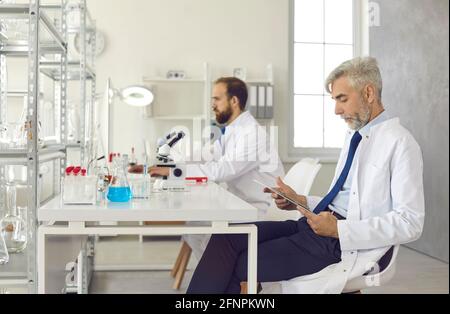 Serious scientists and researchers working sitting at a table in a modern laboratory Stock Photo