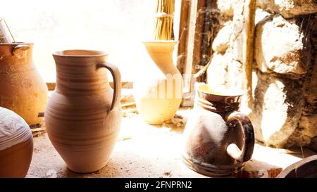 Old clay pot in an old room. Old dusty shelves in a pottery workshop. Bright window light creates a blurry effect and illuminates cobwebs and dust Stock Photo