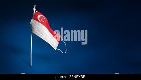 Singapore mask on dark blue background. Waving flag of Singapore painted on medical mask on pole. Virus Attack flag. Concept of The banner of the figh Stock Photo