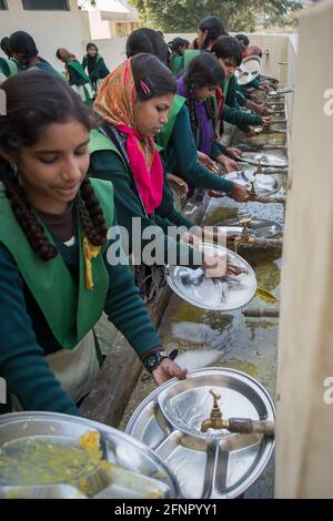 Uttar Pradesh, India. 05-11-2019. Group of indian school girls washing their dishes after finishing lunch. Stock Photo