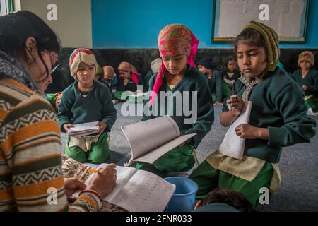 Uttar Pradesh, India. 05-11-2019.Three young girls are approaching their teacher to share their homework during school. Stock Photo