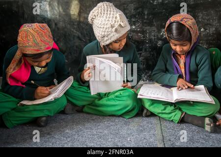 Uttar Pradesh, India. 05-11-2019. Small indian girls are sitting on the floor participating of the school activities doing their homework. Stock Photo