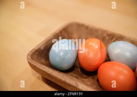 several painted in different color of chicken eggs lie in a wooden tray Stock Photo