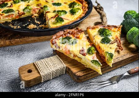Sliced tart with salmon, broccoli and cream on a wooden cutting board. White background. Top view Stock Photo
