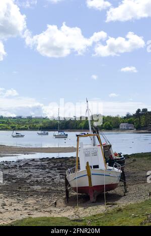 Anglesey, Red Wharf bay. Traditional fishing boat moored on sand flats at low tide. Beautiful seascape on a spring day. Vertical shot - copy space. Stock Photo