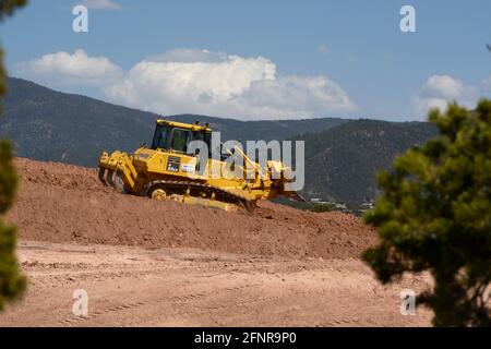 A worker uses a Komatsu 65EX crawler bulldozer to move dirt at a highway improvement job site in Santa Fe, New Mexico. Stock Photo