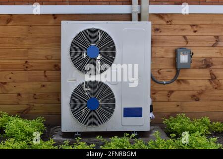 Air conditioner compressor installed outside of the wood house. Stock Photo