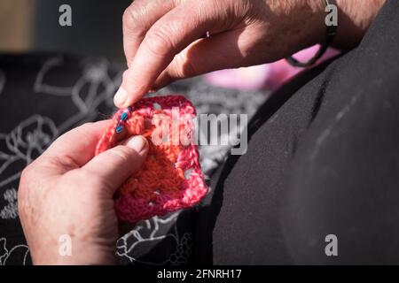 Hands of older woman creates textiles by using a crochet hook to interlock loops of yarn, thread, or strands of other materials Stock Photo