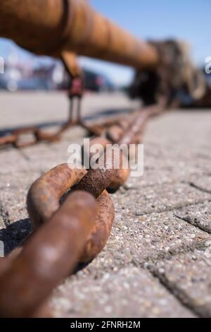 Big rusty chain used for fishing with boat lying in the harbor. Focus on the third ring Stock Photo