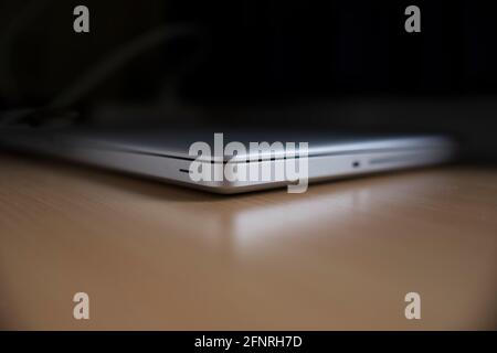 Closed aluminum laptop on a shiny wooden table. It is reflected in the table Stock Photo