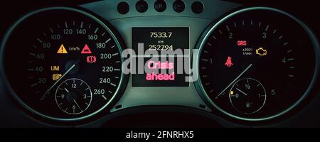 CRISIS AHEAD is written on the dashboard of the car next to the controls and mileage indicators. Financial problems, risks and economic depression con Stock Photo