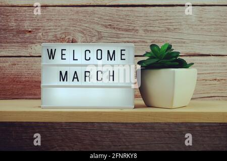 Welcome March word in light box on wooden shelves background Stock Photo