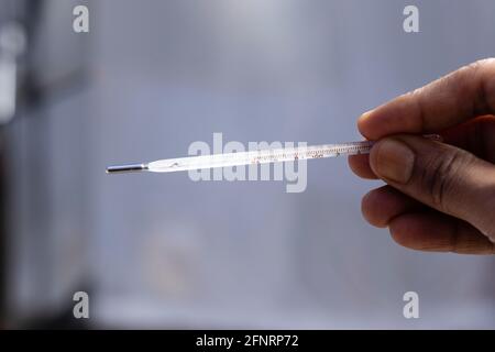 Selective focus on an analog thermometer held in human hand Stock Photo