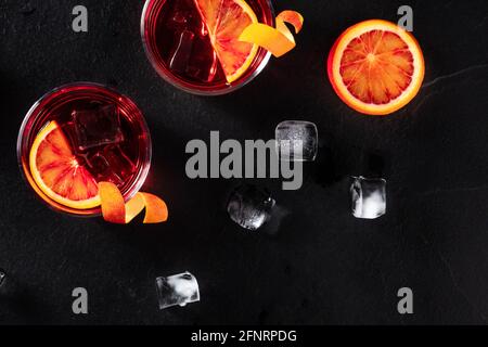 Orange cocktails with ice cubes, top shot on a black slate background