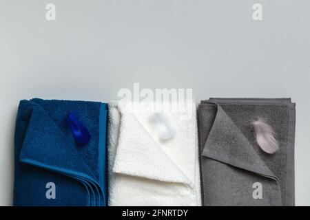 Three terry towels in blue, white and gray with feathers. Flat lay top view with copy space for text. Stock Photo
