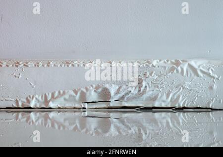 White skirting board damaged by destructive elements from moisture or water. Stock Photo