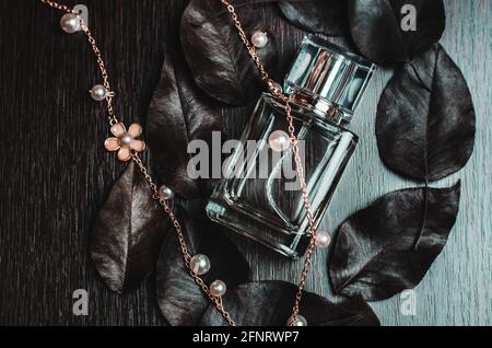 Perfume bottle, autumn leaves and golden decoration on wooden background Stock Photo