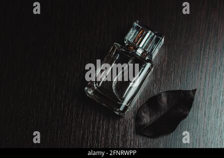 Men's perfume and black leaf on wooden background Stock Photo