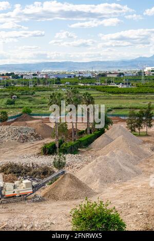 View of the works of the new Burriana institute, machine working pulverizing rubble and accumulating it in small mountains. Work concept Stock Photo