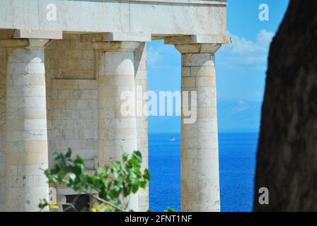 Close up of Doric columns at a temple in Greece with the blue sea in the background. Stock Photo