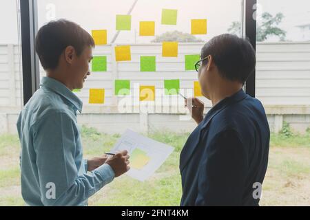 Business people meeting at office use digital tablet and sticky notes to share idea. Brainstorming concept. Stock Photo