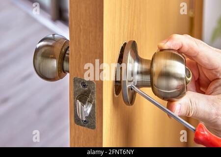 DIY installation of door lock mechanism with handles in new wood panel. Stock Photo