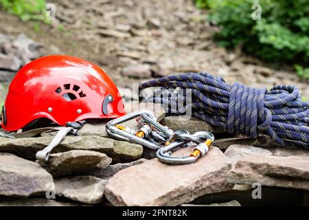 Rope access tools: hard hat, rope, carabiner. Mountaineering equipment on  rocks against a background of rocks and greenery Stock Photo - Alamy