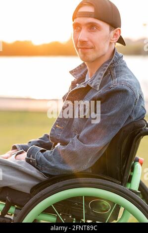 young disabled man in wheelchair walking park Stock Photo