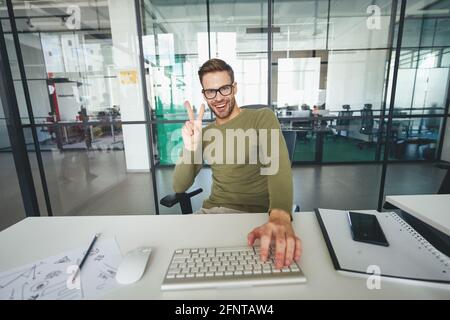 Young man gesturing actively in front of a web-camera Stock Photo