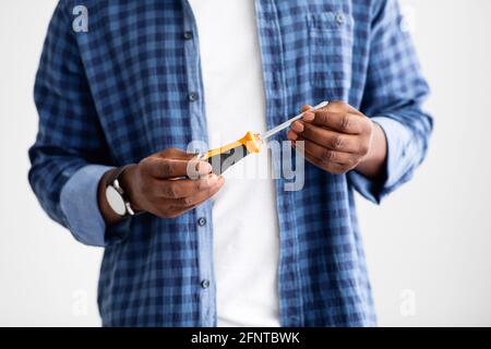 Caucasian male hand holding a red plastic handle screwdriver isolated on gray background. Stock Photo