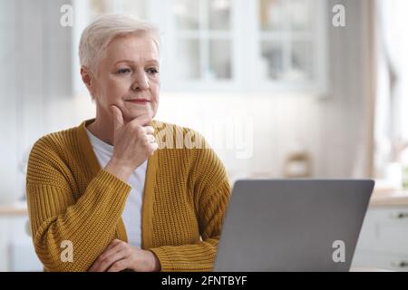 Attractive elderly woman sitting in front of laptop Stock Photo