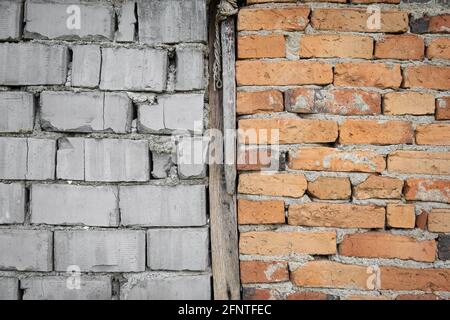 Old wooden beam separating red, rustic brick wall from a wall made from white blocks Stock Photo